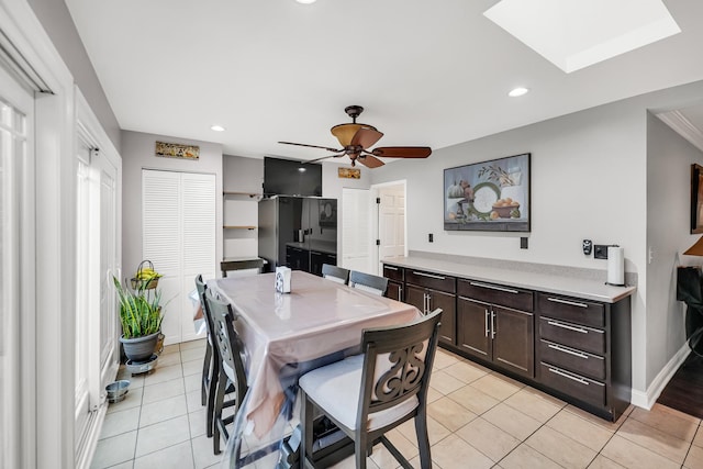 dining area featuring a skylight, ceiling fan, and light tile patterned floors