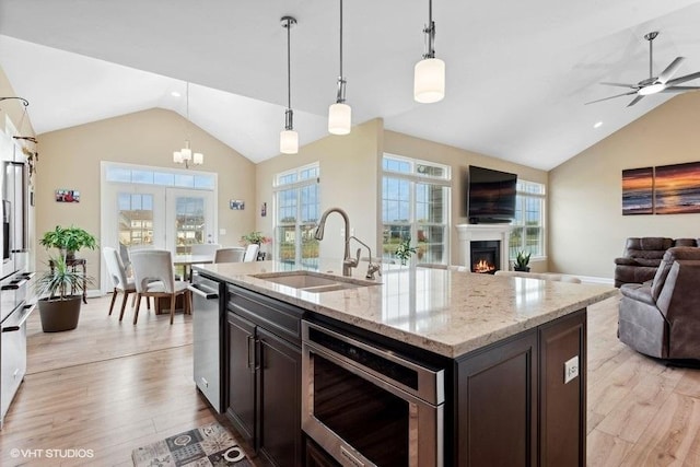 kitchen with a kitchen island with sink, sink, light hardwood / wood-style flooring, decorative light fixtures, and dark brown cabinetry