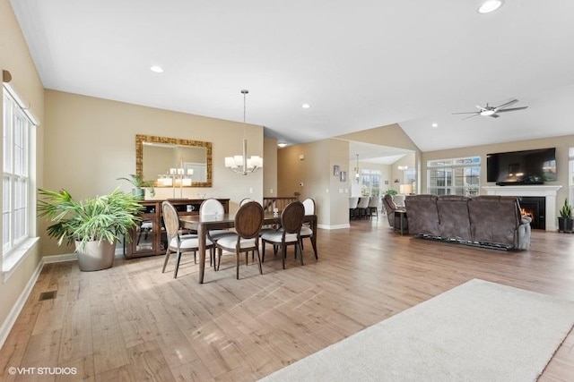 dining space featuring ceiling fan with notable chandelier, lofted ceiling, and light hardwood / wood-style flooring