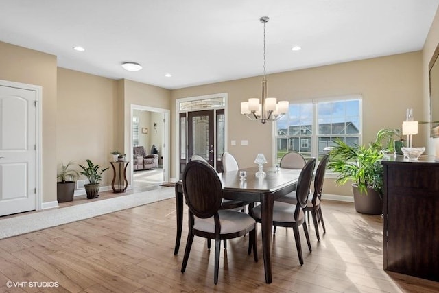 dining space with a notable chandelier and light hardwood / wood-style floors