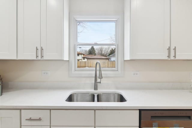 kitchen with dishwashing machine, sink, white cabinets, and light stone countertops