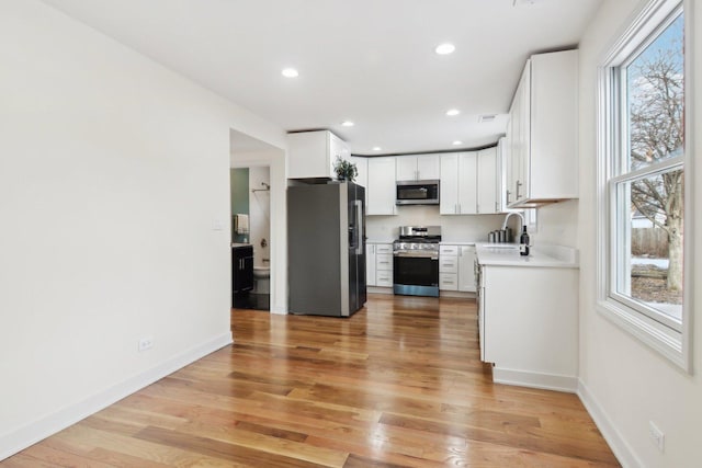 kitchen with white cabinetry, sink, light wood-type flooring, and appliances with stainless steel finishes