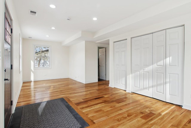 unfurnished bedroom featuring wood-type flooring and multiple closets