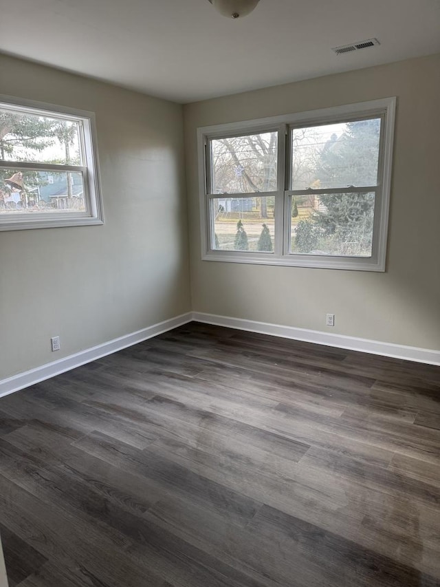 unfurnished room with dark hardwood / wood-style flooring and a healthy amount of sunlight