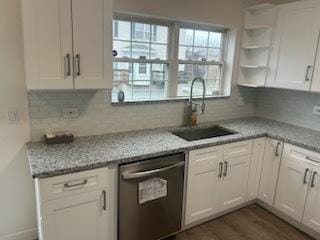 kitchen with white cabinetry, dishwasher, light stone countertops, and sink