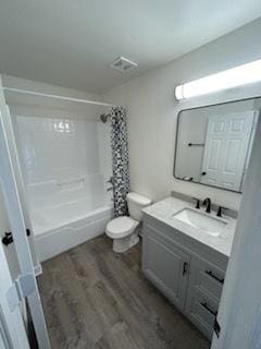 full bathroom featuring hardwood / wood-style floors, vanity, toilet, and shower / tub combo