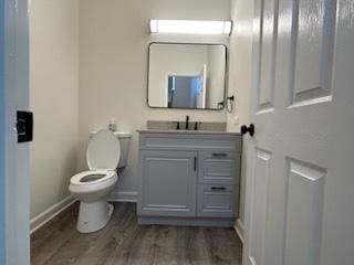 bathroom with hardwood / wood-style floors, vanity, and toilet