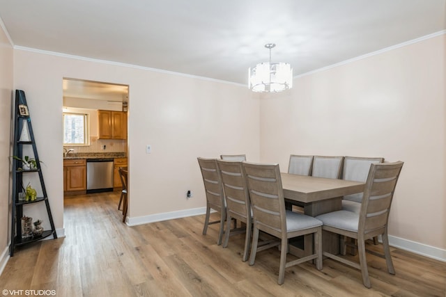 dining room with light hardwood / wood-style flooring, an inviting chandelier, crown molding, and sink