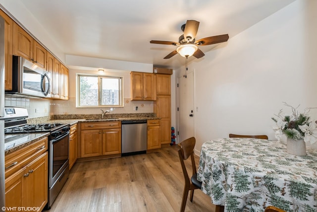 kitchen featuring decorative backsplash, appliances with stainless steel finishes, sink, stone counters, and light hardwood / wood-style floors