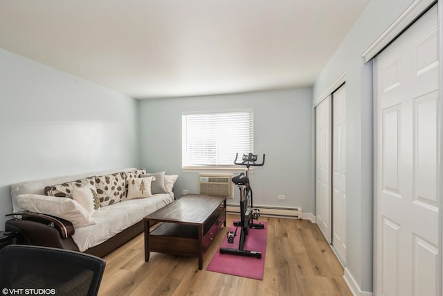 workout room featuring a wall mounted AC, a baseboard heating unit, and light wood-type flooring