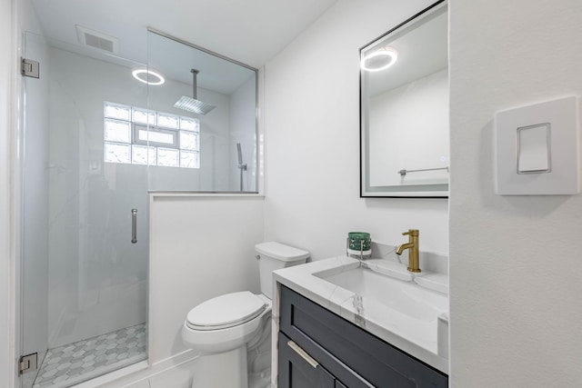 bathroom featuring vanity, a shower with shower door, and toilet