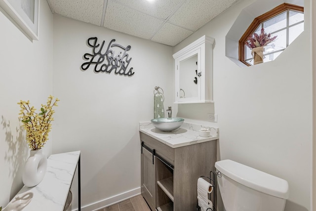 bathroom with vanity, hardwood / wood-style floors, a paneled ceiling, and toilet