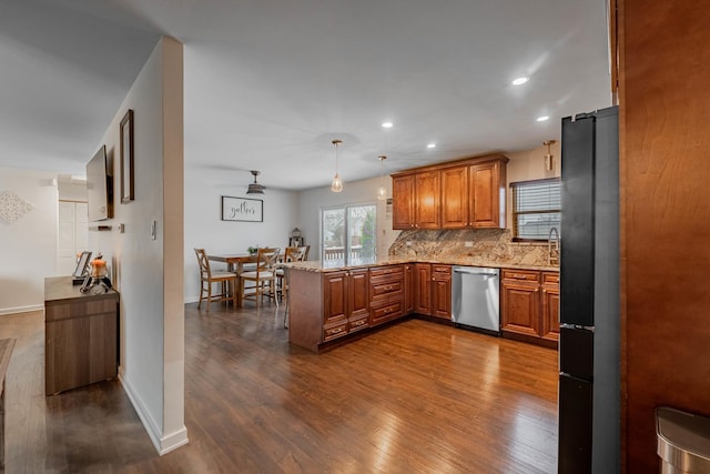 kitchen featuring dark hardwood / wood-style flooring, stainless steel dishwasher, kitchen peninsula, pendant lighting, and decorative backsplash