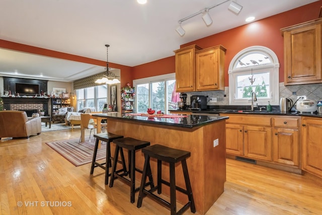 kitchen featuring a brick fireplace, a center island, light hardwood / wood-style flooring, and a breakfast bar area