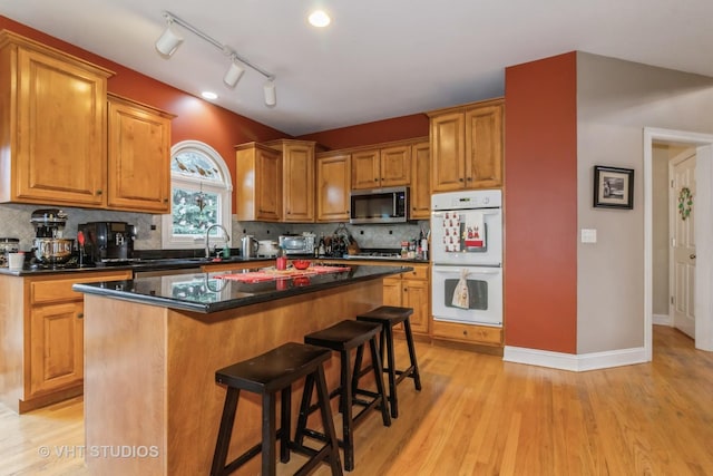 kitchen featuring a kitchen bar, white double oven, a center island, and light hardwood / wood-style flooring