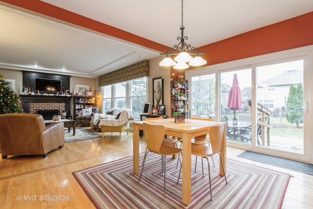 dining space with an inviting chandelier, a brick fireplace, and hardwood / wood-style flooring