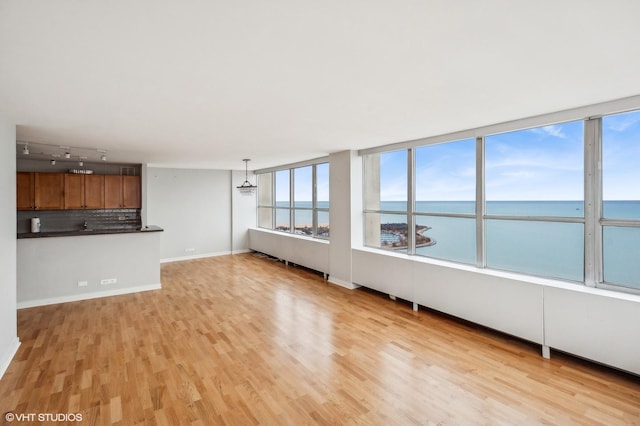 unfurnished living room featuring a water view and light hardwood / wood-style flooring