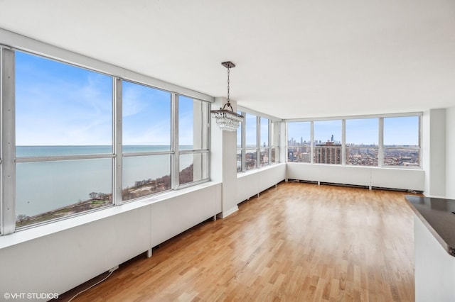 unfurnished sunroom featuring a water view and a chandelier