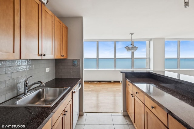 kitchen with sink, light tile patterned floors, pendant lighting, decorative backsplash, and a water view