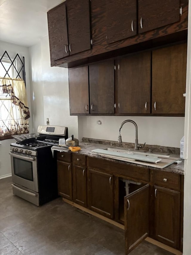 kitchen with stainless steel gas range oven, dark brown cabinetry, and sink