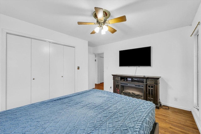 bedroom featuring a fireplace, hardwood / wood-style floors, and ceiling fan