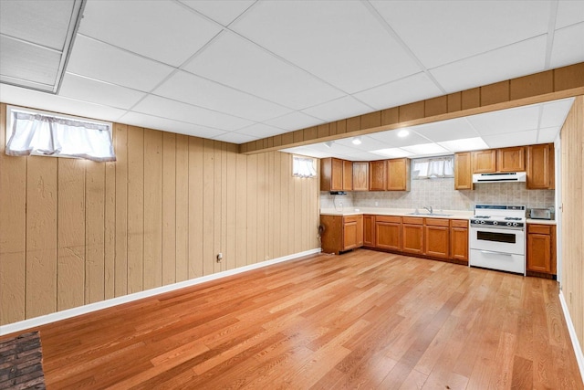 kitchen with sink, tasteful backsplash, a paneled ceiling, white stove, and light wood-type flooring