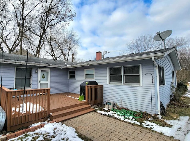 snow covered rear of property featuring a deck