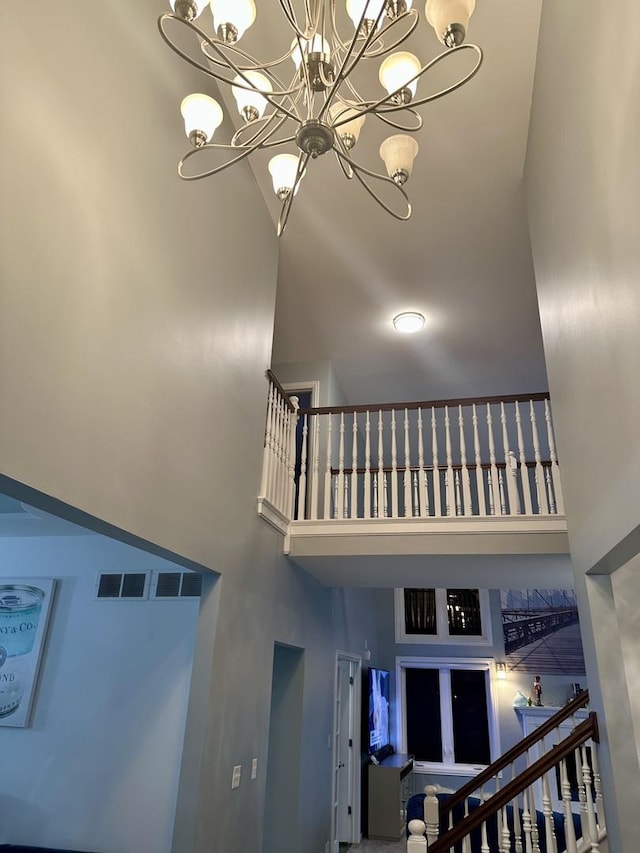 staircase with a chandelier and a towering ceiling