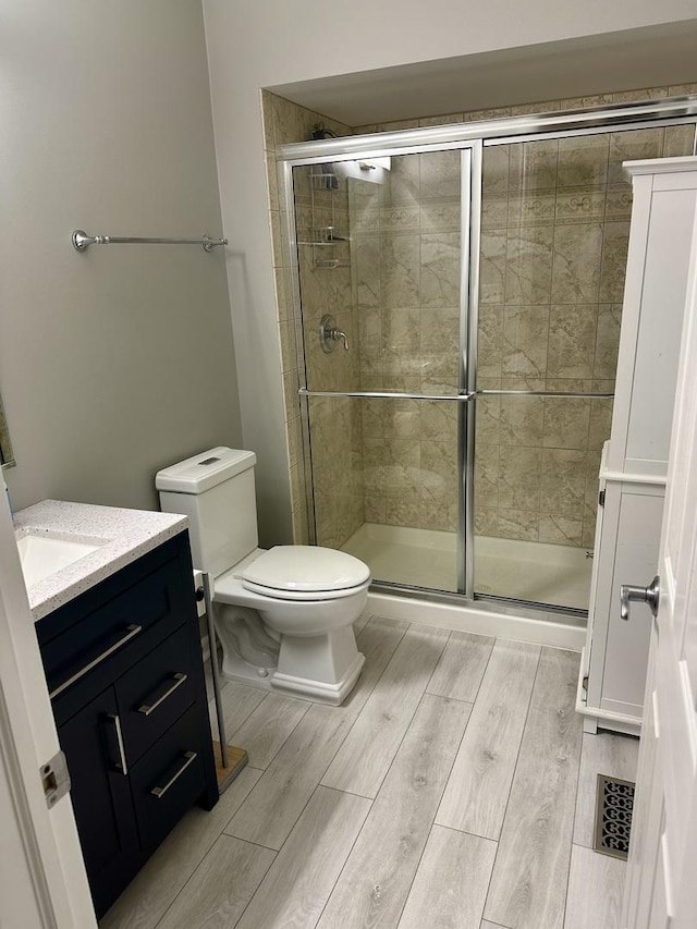 bathroom with vanity, a shower with shower door, and toilet