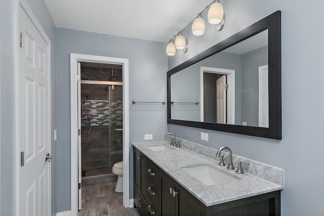 bathroom with tiled shower, hardwood / wood-style floors, vanity, and toilet