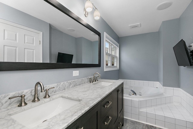 bathroom featuring tiled tub, vanity, and wood-type flooring