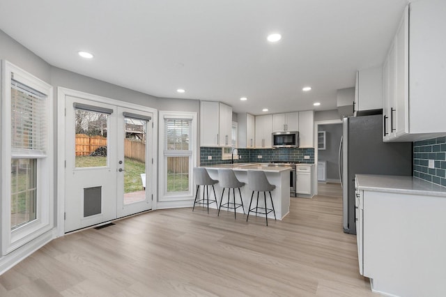 kitchen featuring stainless steel appliances, white cabinetry, tasteful backsplash, and a breakfast bar area