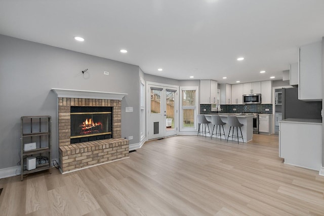 living room with light hardwood / wood-style floors, sink, and a fireplace