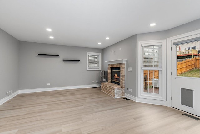 unfurnished living room featuring a fireplace, plenty of natural light, and light wood-type flooring