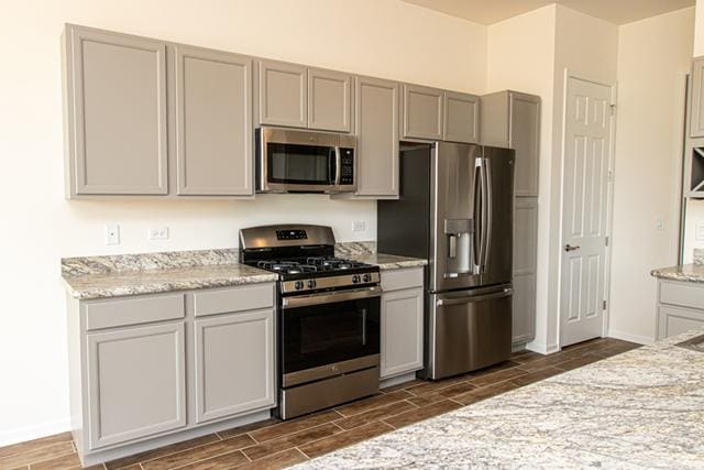 kitchen featuring gray cabinetry, light stone countertops, and stainless steel appliances