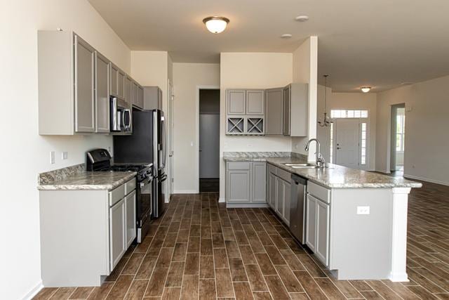 kitchen featuring sink, stainless steel appliances, light stone counters, kitchen peninsula, and gray cabinets