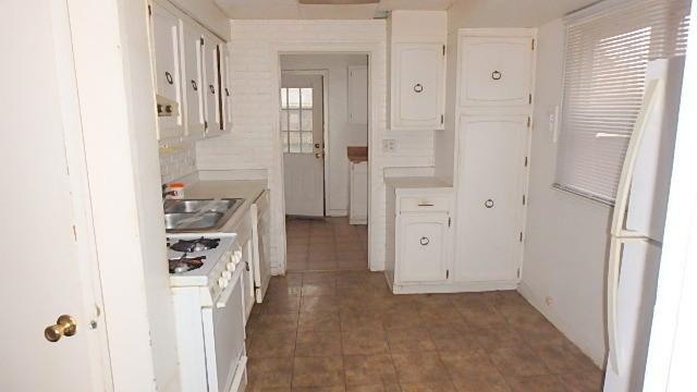 kitchen featuring white appliances, white cabinetry, and sink