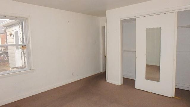 unfurnished bedroom featuring dark colored carpet and a closet