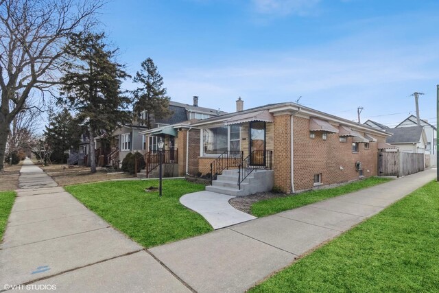 bungalow-style home featuring brick siding, a front lawn, a chimney, and fence