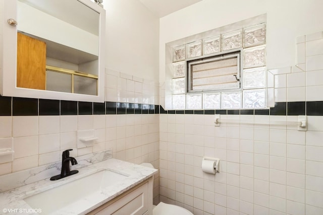 full bathroom with tile walls, vanity, toilet, and an enclosed shower