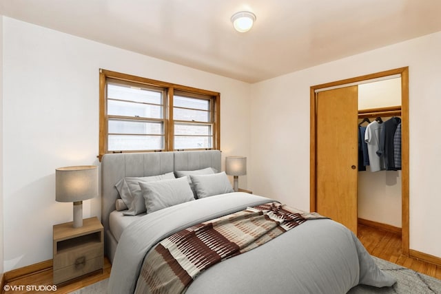 bedroom with a closet, light wood-style flooring, and baseboards