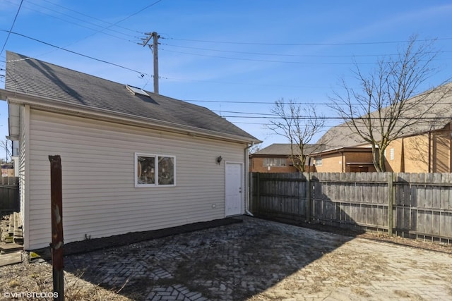 back of property featuring a shingled roof and fence