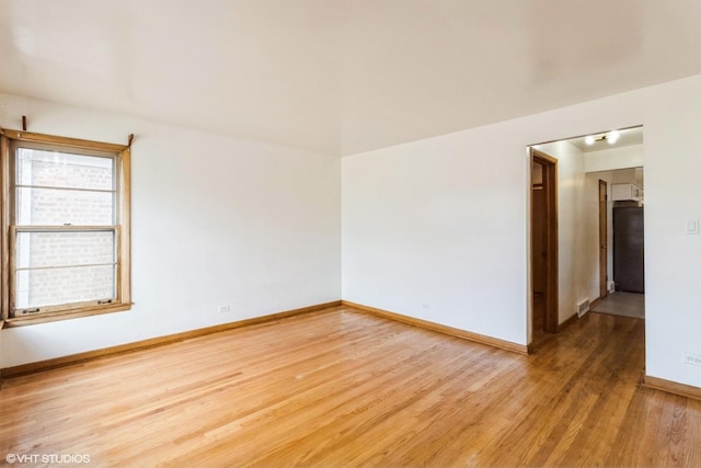 spare room featuring light wood finished floors and baseboards