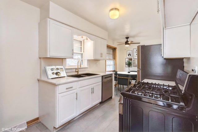 kitchen featuring light countertops, appliances with stainless steel finishes, white cabinetry, a sink, and ceiling fan