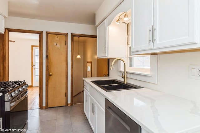 kitchen featuring light tile patterned floors, white cabinets, light stone counters, stainless steel appliances, and a sink