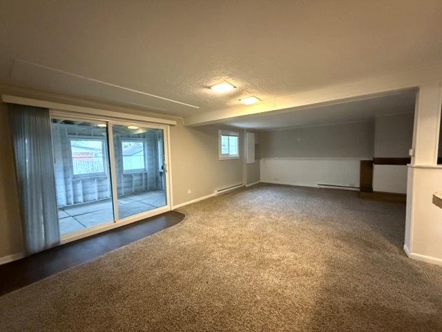 basement with carpet flooring, a textured ceiling, and baseboard heating