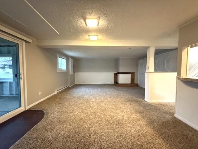 basement with carpet, a textured ceiling, and a baseboard heating unit