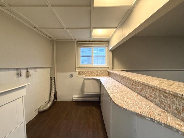 clothes washing area with baseboard heating and dark wood-type flooring