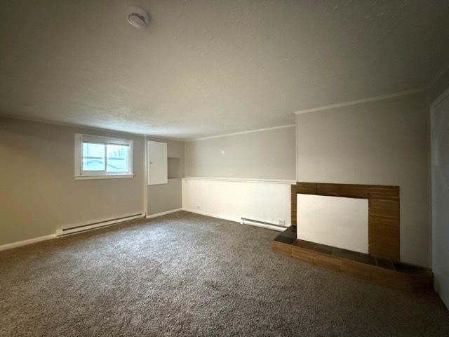 basement featuring carpet, a baseboard radiator, and ornamental molding