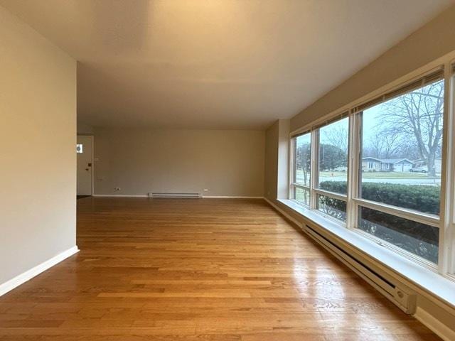 empty room featuring light wood-type flooring and a baseboard heating unit